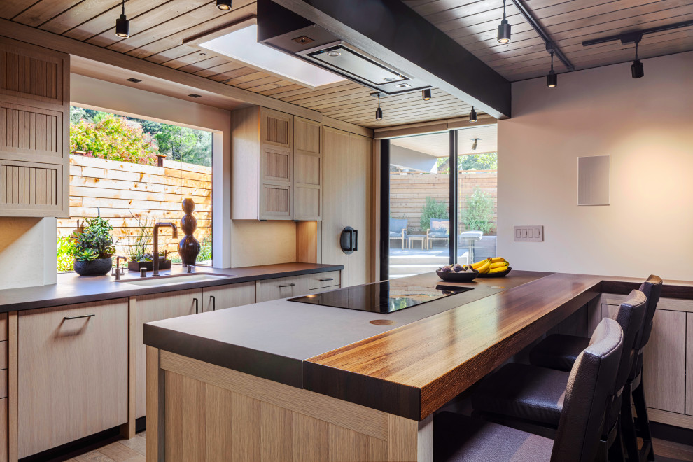 Exemple d'une cuisine parallèle et encastrable asiatique en bois clair avec un évier encastré, un placard à porte plane, une péninsule, un plan de travail gris et un plafond en bois.