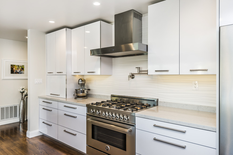 Eat-in kitchen - mid-sized contemporary galley medium tone wood floor eat-in kitchen idea in San Francisco with an undermount sink, flat-panel cabinets, white cabinets, quartz countertops, white backsplash, ceramic backsplash, stainless steel appliances and an island
