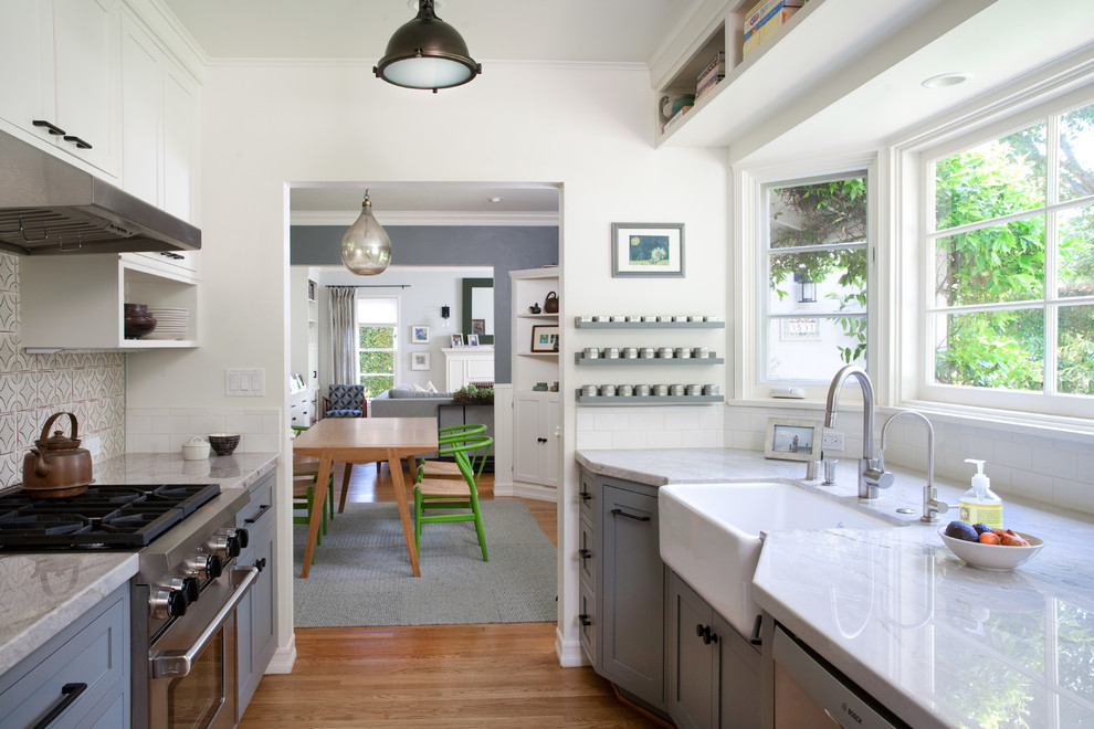 Klassisk inredning av ett stort kök, med en rustik diskho, skåp i shakerstil, grå skåp, marmorbänkskiva, vitt stänkskydd, stänkskydd i tunnelbanekakel, rostfria vitvaror och mellanmörkt trägolv