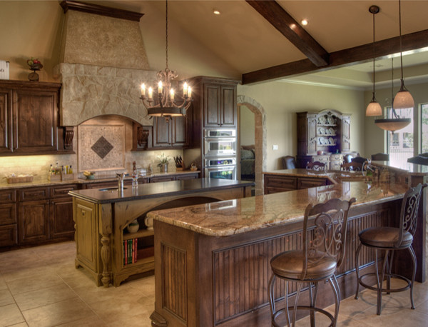 Example of a large classic l-shaped porcelain tile eat-in kitchen design in Houston with an undermount sink, raised-panel cabinets, medium tone wood cabinets, granite countertops, beige backsplash, stone tile backsplash, stainless steel appliances and two islands