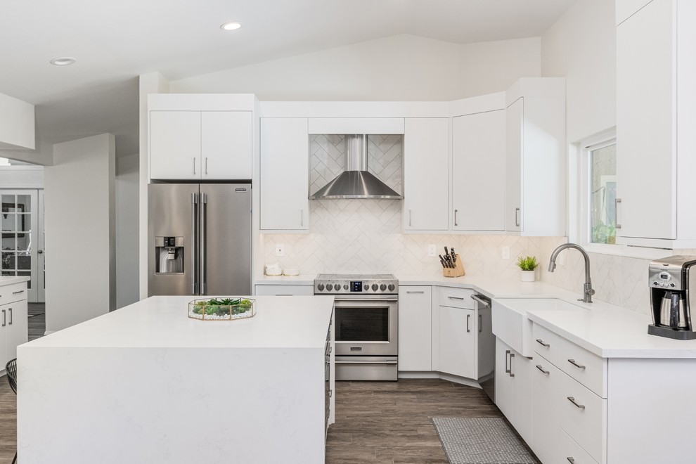 Eat-in kitchen - mid-sized 1950s l-shaped porcelain tile and beige floor eat-in kitchen idea in Phoenix with a farmhouse sink, flat-panel cabinets, white cabinets, quartzite countertops, white backsplash, porcelain backsplash, stainless steel appliances, an island and white countertops