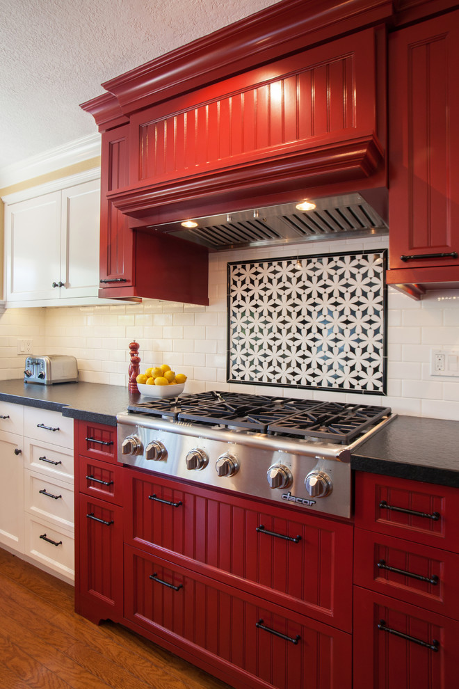 Eat-in kitchen - mid-sized traditional l-shaped medium tone wood floor eat-in kitchen idea in Orange County with an undermount sink, white backsplash, subway tile backsplash, stainless steel appliances, an island, beaded inset cabinets, red cabinets and granite countertops