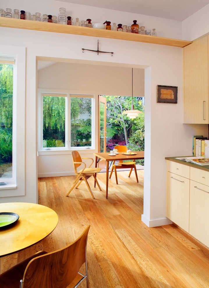 Modelo de cocina comedor actual grande sin isla con armarios con paneles lisos, puertas de armario de madera clara, fregadero bajoencimera, electrodomésticos de acero inoxidable y suelo de madera en tonos medios