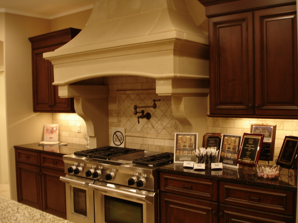 Bild på ett stort vintage kök och matrum, med en undermonterad diskho, luckor med upphöjd panel, skåp i mörkt trä, granitbänkskiva, beige stänkskydd, stänkskydd i stenkakel, rostfria vitvaror och travertin golv
