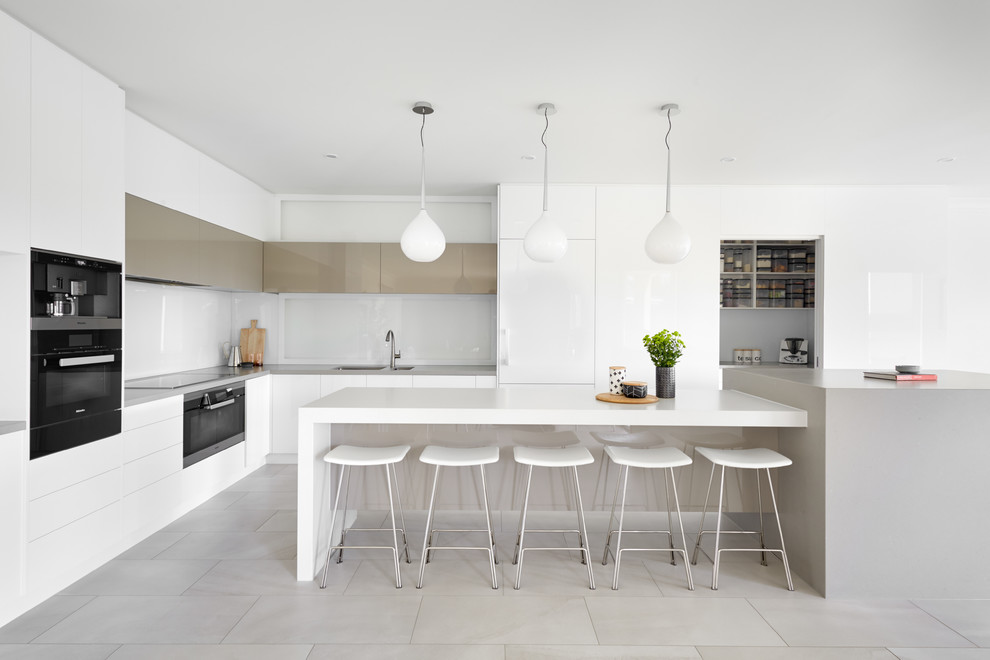 Inspiration for a mid-sized contemporary l-shaped kitchen pantry remodel in Melbourne with a double-bowl sink, beaded inset cabinets, white cabinets, solid surface countertops, white backsplash, porcelain backsplash, stainless steel appliances, an island and white countertops