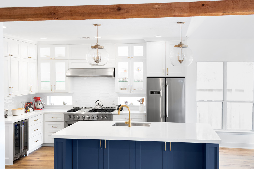 Example of a mid-sized transitional l-shaped light wood floor and orange floor eat-in kitchen design in Houston with an undermount sink, recessed-panel cabinets, blue cabinets, quartz countertops, white backsplash, subway tile backsplash, stainless steel appliances, an island and white countertops