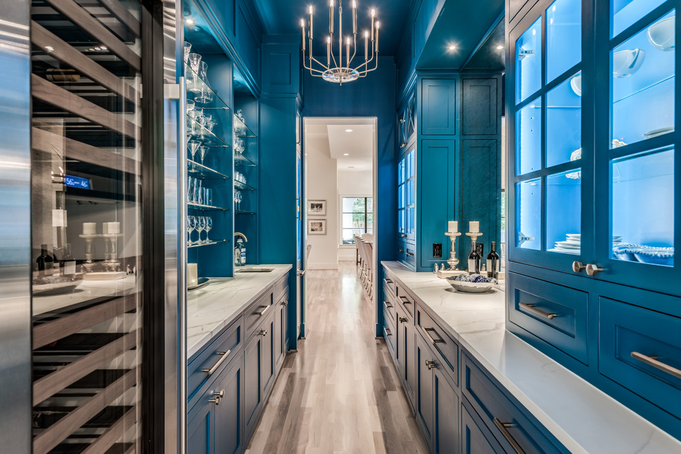 Exempel på ett mycket stort klassiskt vit vitt kök, med en undermonterad diskho, skåp i shakerstil, blå skåp, bänkskiva i kvarts, stänkskydd med metallisk yta, spegel som stänkskydd, rostfria vitvaror, ljust trägolv och beiget golv