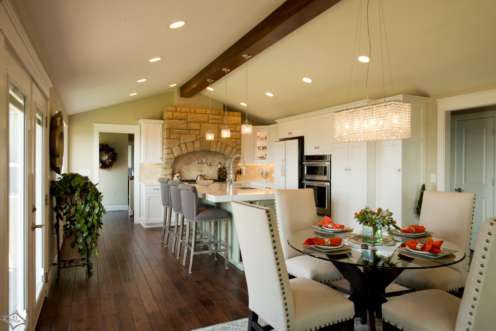 Medium sized traditional l-shaped kitchen/diner in Seattle with a submerged sink, recessed-panel cabinets, white cabinets, engineered stone countertops, beige splashback, ceramic splashback, stainless steel appliances, dark hardwood flooring and an island.