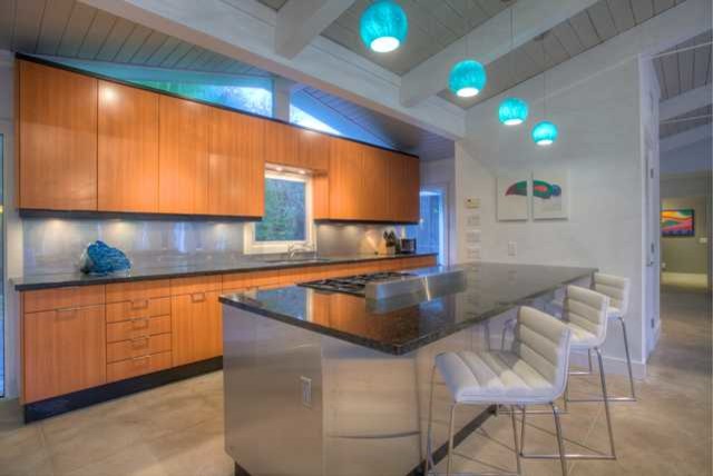 Exempel på ett retro linjärt kök och matrum, med en undermonterad diskho, släta luckor, skåp i mellenmörkt trä, granitbänkskiva, stänkskydd med metallisk yta, stänkskydd i metallkakel och rostfria vitvaror