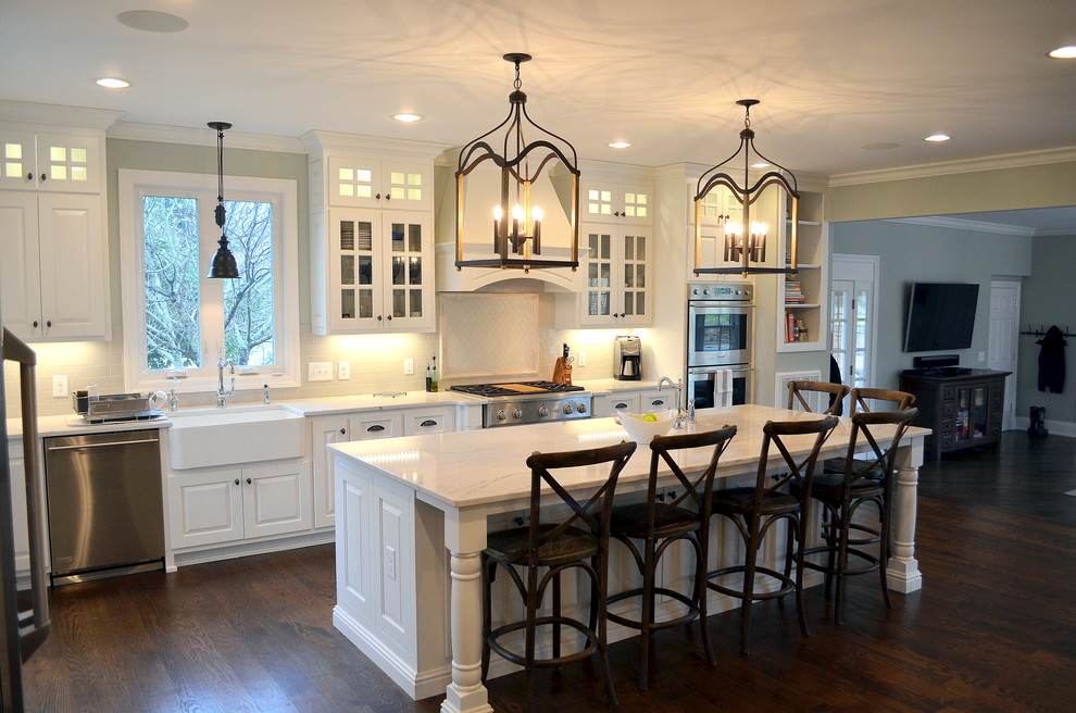 Example of a huge classic l-shaped dark wood floor open concept kitchen design in Nashville with a farmhouse sink, raised-panel cabinets, white cabinets, quartz countertops, white backsplash, ceramic backsplash, stainless steel appliances and an island