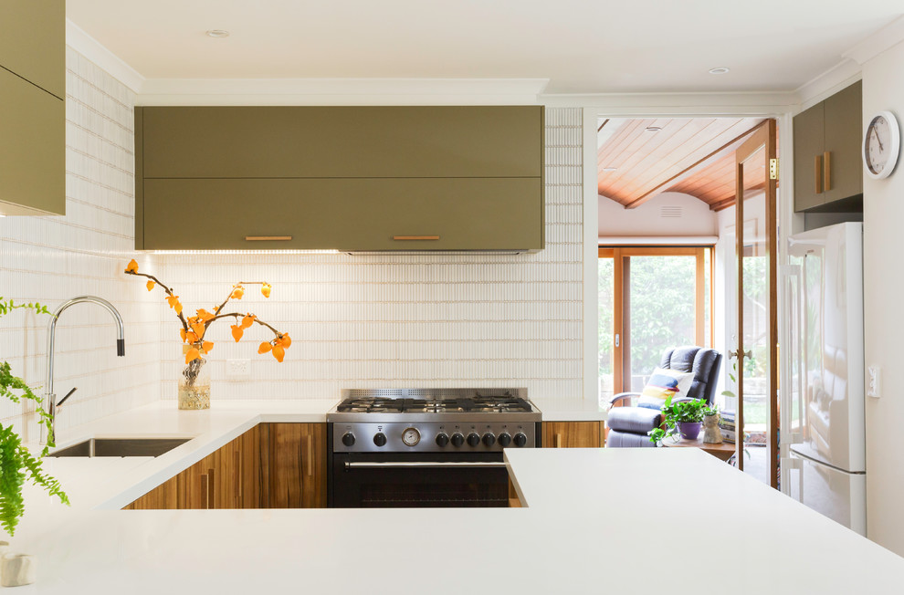 Inspiration for a large contemporary u-shaped kitchen pantry in Melbourne with a built-in sink, beaded cabinets, green cabinets, composite countertops, white splashback, metro tiled splashback, stainless steel appliances, limestone flooring, an island and white worktops.