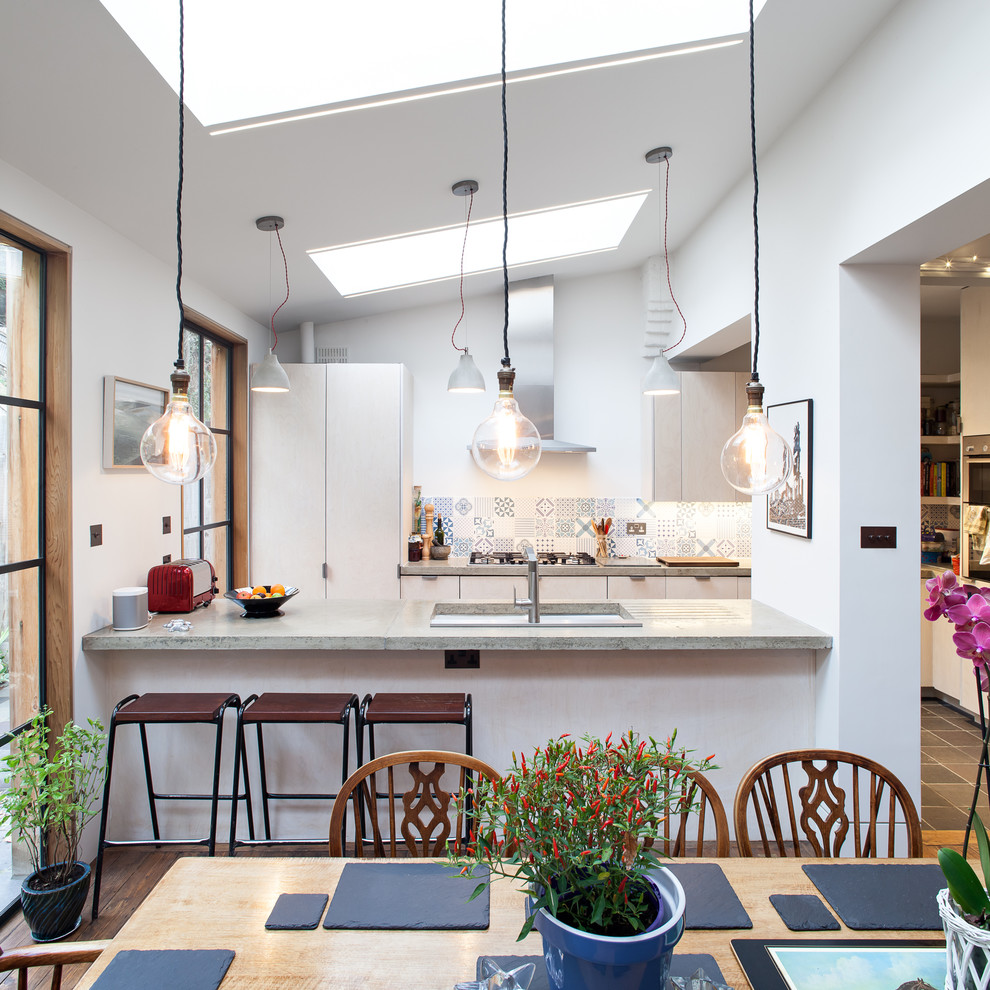 Immagine di una cucina abitabile design con ante lisce, ante bianche e paraspruzzi multicolore