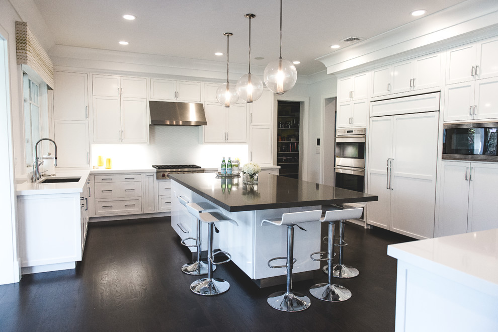 Eat-in kitchen - large transitional u-shaped dark wood floor eat-in kitchen idea in New York with an undermount sink, shaker cabinets, white cabinets, white backsplash, stainless steel appliances, an island, solid surface countertops and ceramic backsplash