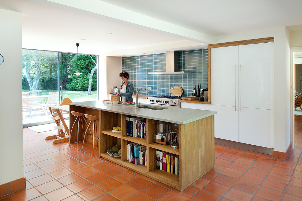 Large contemporary galley kitchen/diner in Hampshire with a double-bowl sink, flat-panel cabinets, white cabinets, ceramic splashback, stainless steel appliances, terracotta flooring and an island.