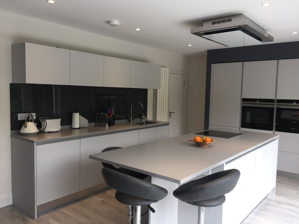 Design ideas for a medium sized modern kitchen in Dublin with flat-panel cabinets, grey cabinets, engineered stone countertops, multi-coloured splashback, mirror splashback, concrete flooring, an island and grey floors.