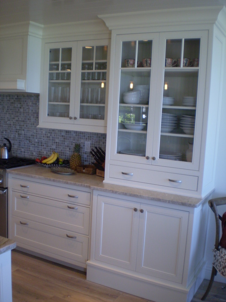 Exotisk inredning av ett mellanstort kök, med en dubbel diskho, luckor med profilerade fronter, vita skåp, bänkskiva i kvartsit, flerfärgad stänkskydd, stänkskydd i mosaik, rostfria vitvaror, ljust trägolv och en köksö