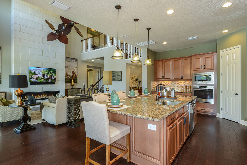 Example of a mid-sized southwest l-shaped dark wood floor and brown floor kitchen design in Tampa with raised-panel cabinets, light wood cabinets, stainless steel appliances and an island