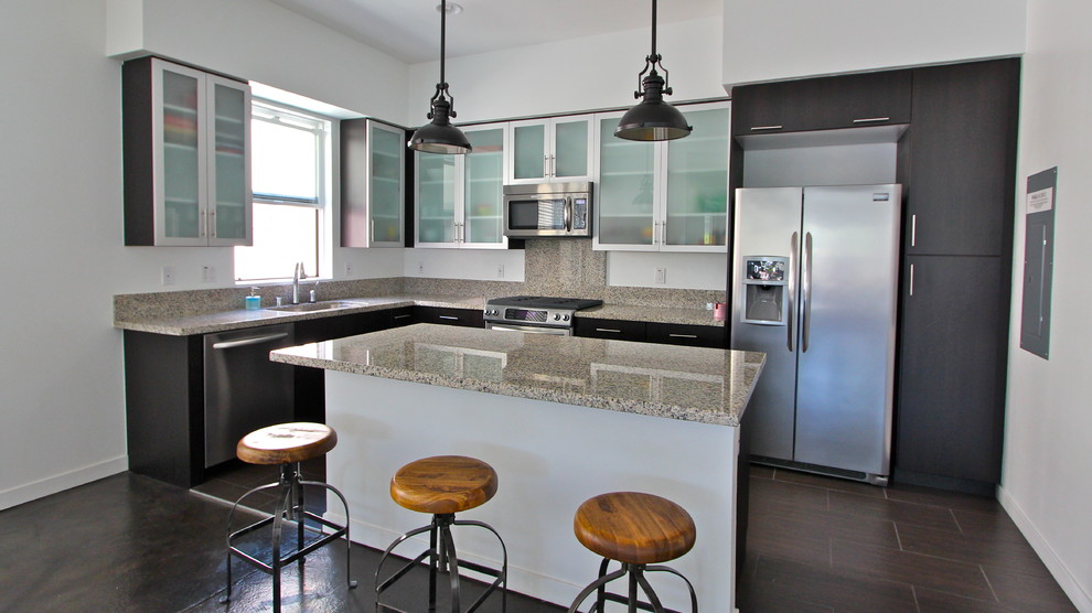 Esempio di un cucina con isola centrale minimalista con ante di vetro, ante in acciaio inossidabile, top in granito, elettrodomestici in acciaio inossidabile e pavimento in gres porcellanato