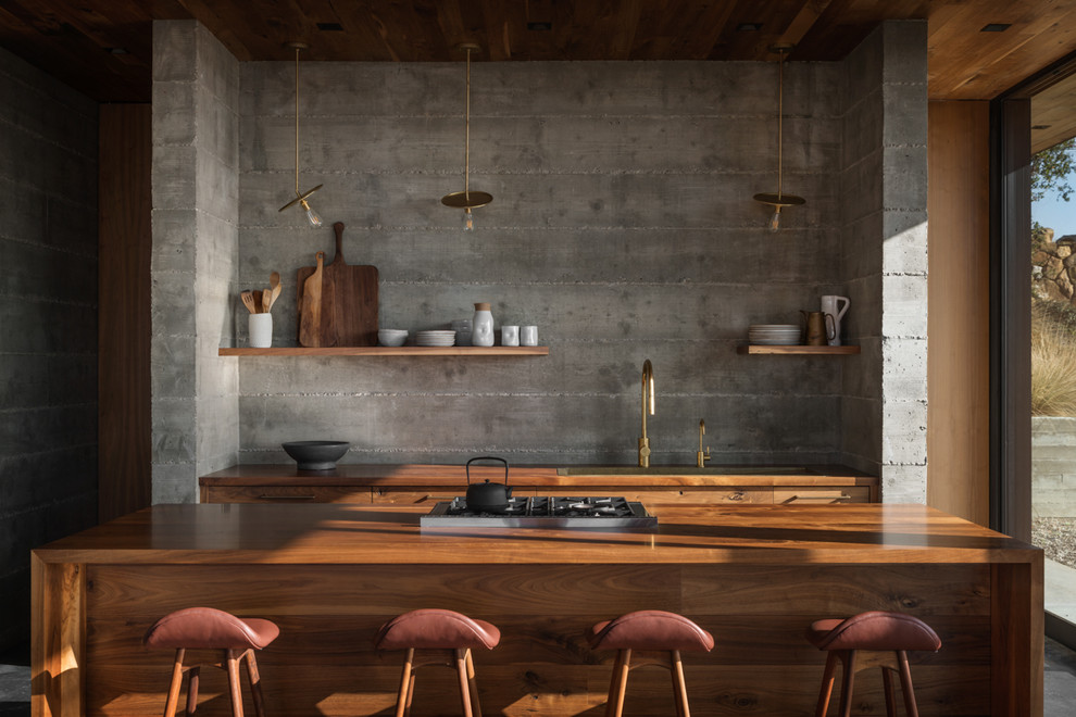 Imagen de cocina contemporánea con armarios con paneles lisos, puertas de armario de madera oscura, encimera de madera, suelo de cemento, una isla, suelo gris y encimeras marrones