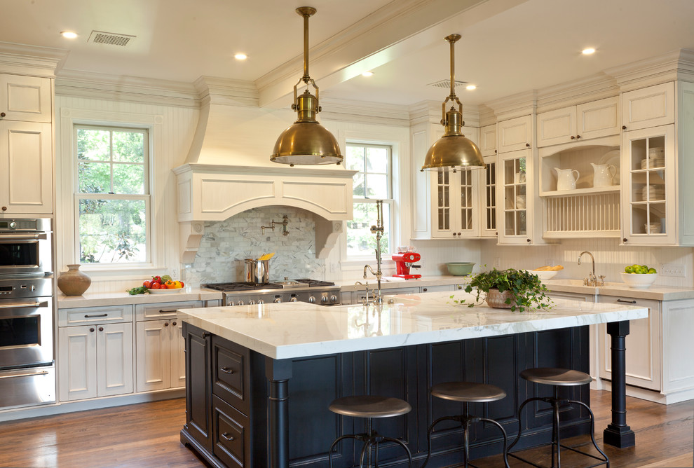 Eat-in kitchen - large traditional u-shaped dark wood floor eat-in kitchen idea in Santa Barbara with a farmhouse sink, recessed-panel cabinets, white cabinets, marble countertops, white backsplash, stainless steel appliances and an island
