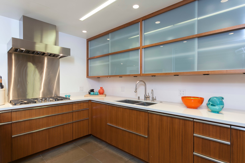 Example of a trendy l-shaped kitchen design in Santa Barbara with a double-bowl sink, glass-front cabinets, medium tone wood cabinets, metallic backsplash and metal backsplash