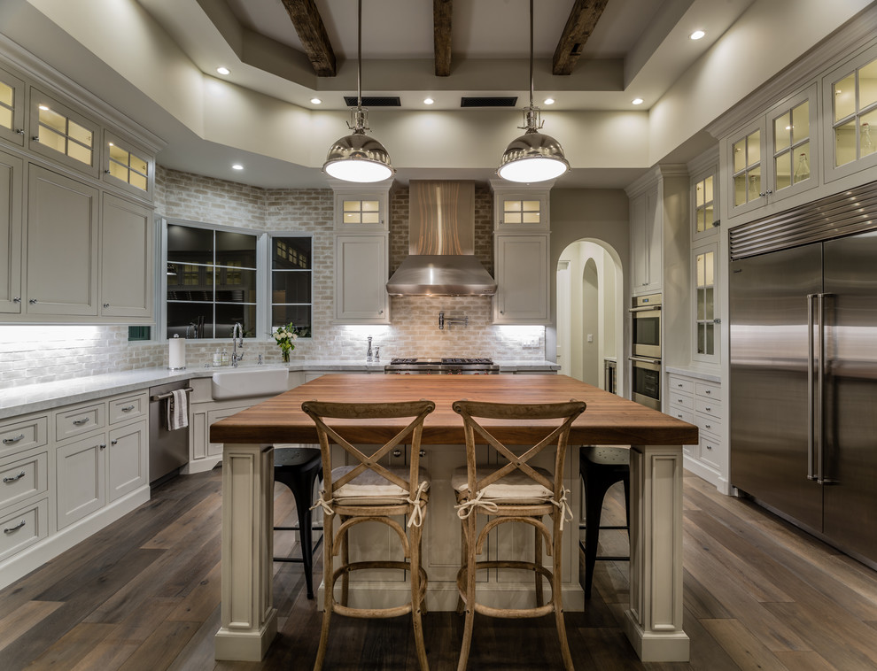 Klassische Küche in U-Form mit Landhausspüle, Schrankfronten mit vertiefter Füllung, weißen Schränken, Küchenrückwand in Beige, Küchengeräten aus Edelstahl und dunklem Holzboden in Phoenix