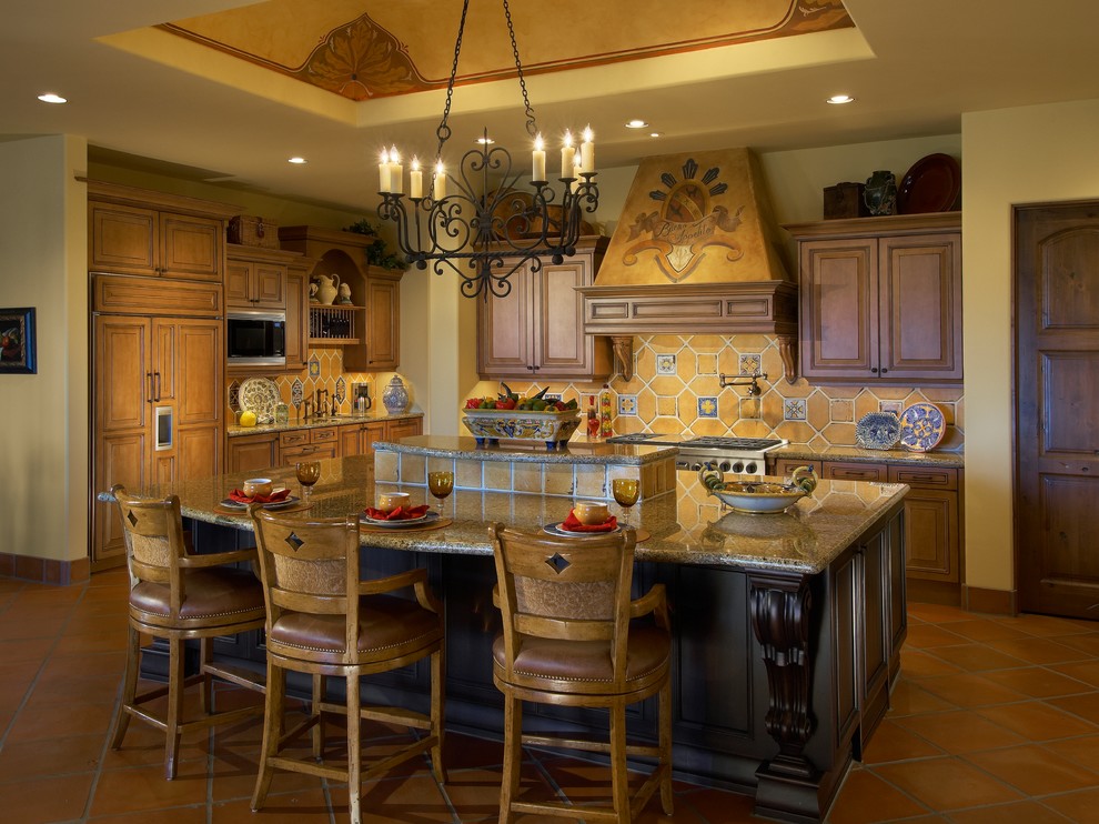 Inredning av ett medelhavsstil stort kök, med granitbänkskiva, en dubbel diskho, luckor med upphöjd panel, skåp i mellenmörkt trä, gult stänkskydd, stänkskydd i keramik, rostfria vitvaror, klinkergolv i terrakotta och en köksö