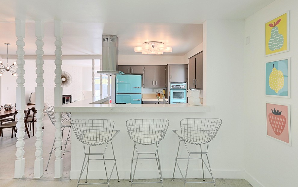 Immagine di una piccola cucina moderna con ante lisce, ante grigie, top in quarzo composito, paraspruzzi arancione, paraspruzzi in gres porcellanato, elettrodomestici colorati e pavimento in cemento