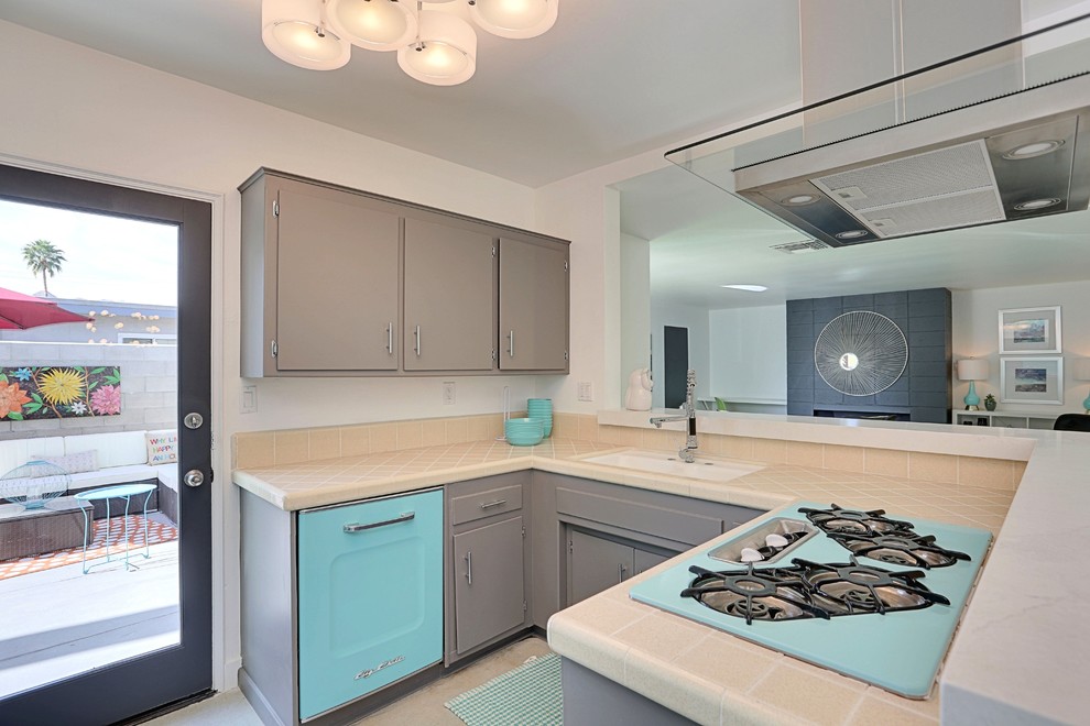 Inspiration for a small retro u-shaped open plan kitchen in Phoenix with an integrated sink, flat-panel cabinets, grey cabinets, tile countertops, orange splashback, porcelain splashback, coloured appliances and concrete flooring.