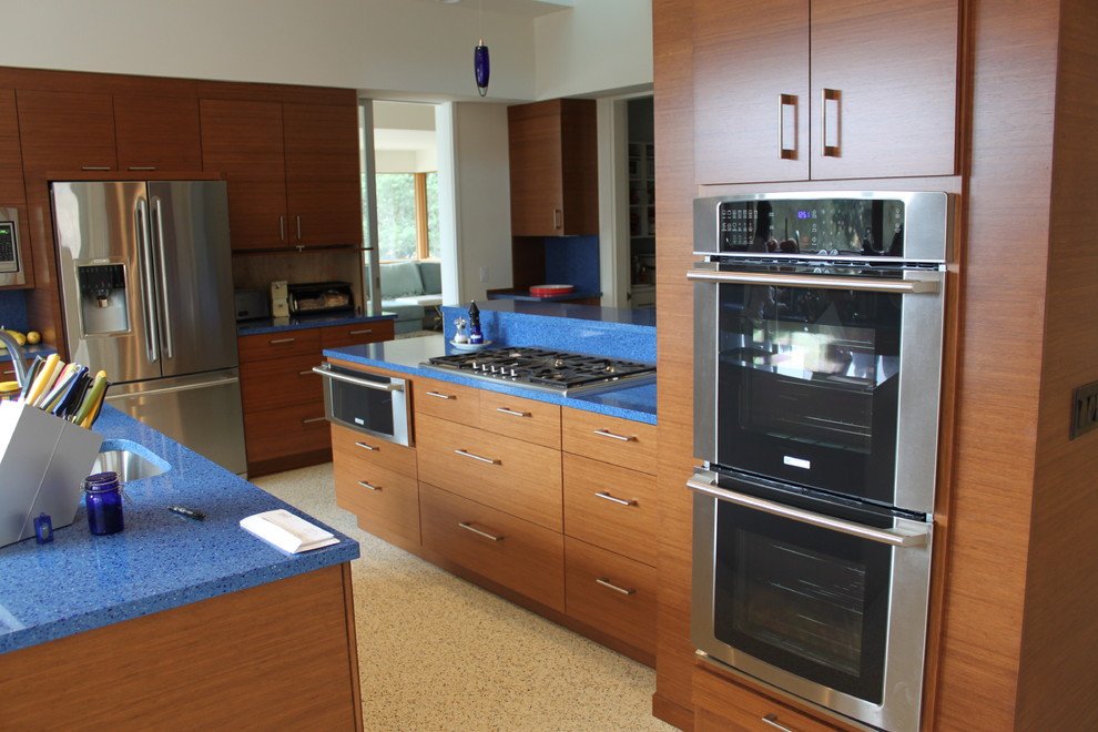Example of a mid-sized galley eat-in kitchen design in San Francisco with a single-bowl sink, flat-panel cabinets, light wood cabinets, terrazzo countertops, blue backsplash, stainless steel appliances and an island