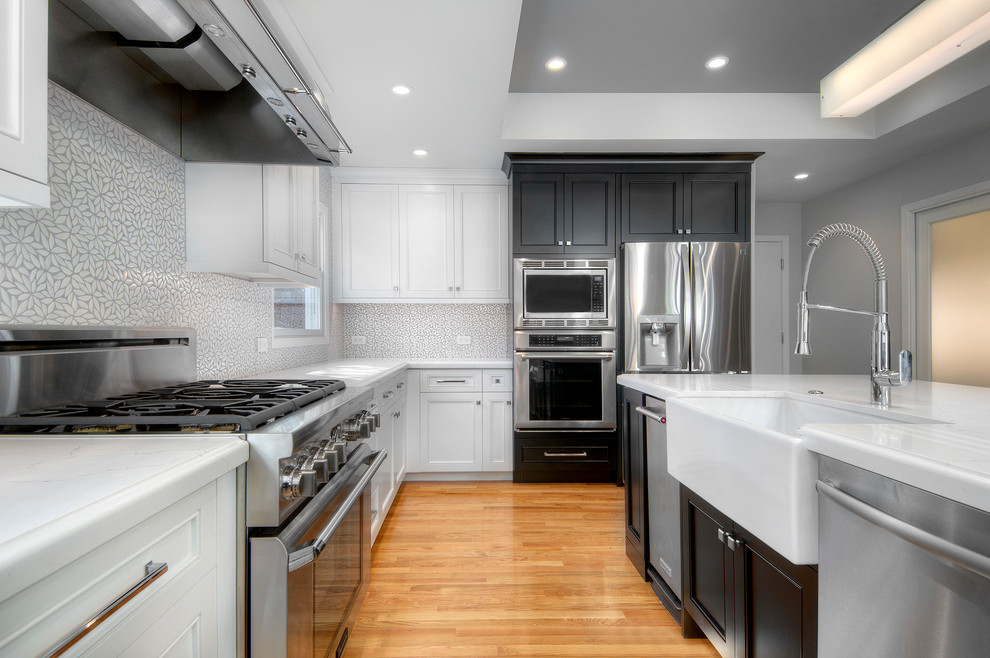 Example of a large transitional l-shaped light wood floor open concept kitchen design in San Francisco with a farmhouse sink, recessed-panel cabinets, white cabinets, quartz countertops, gray backsplash, ceramic backsplash, stainless steel appliances and an island