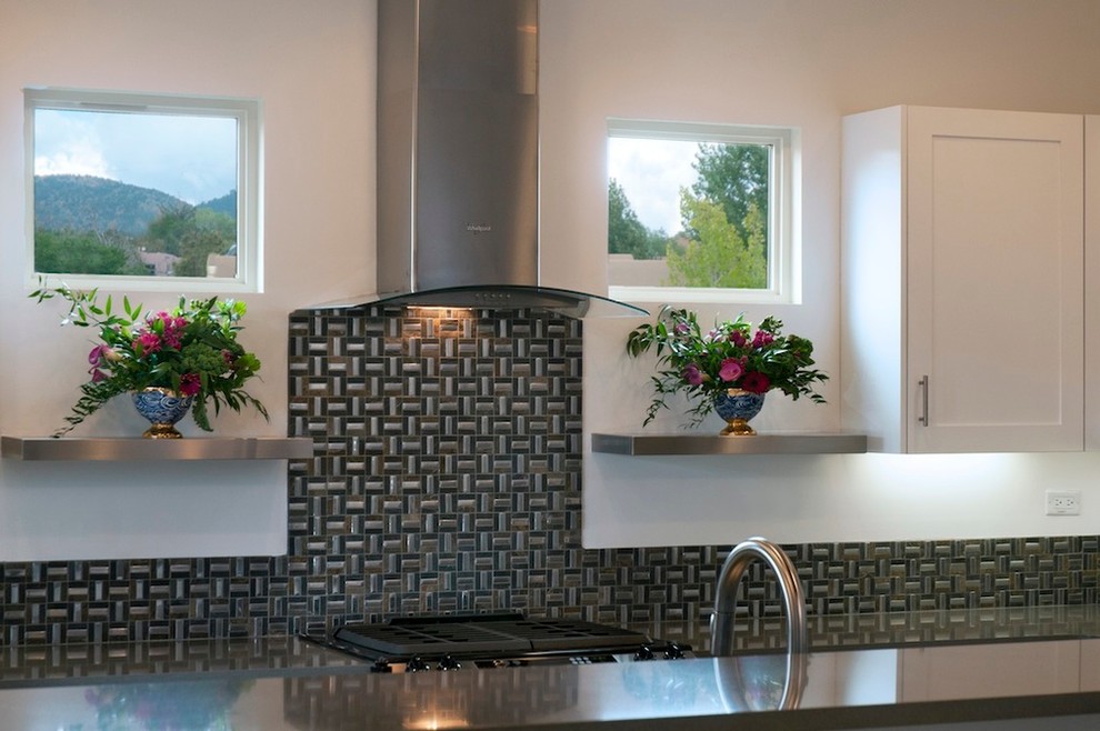 Modern inredning av ett mellanstort kök, med en dubbel diskho, vita skåp, bänkskiva i kvartsit, stänkskydd med metallisk yta, stänkskydd i glaskakel, rostfria vitvaror och klinkergolv i porslin