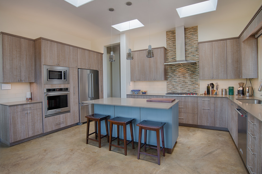 Photo of a large contemporary u-shaped kitchen/diner in Albuquerque with a double-bowl sink, flat-panel cabinets, medium wood cabinets, quartz worktops, beige splashback, glass tiled splashback, stainless steel appliances, concrete flooring, an island and beige floors.