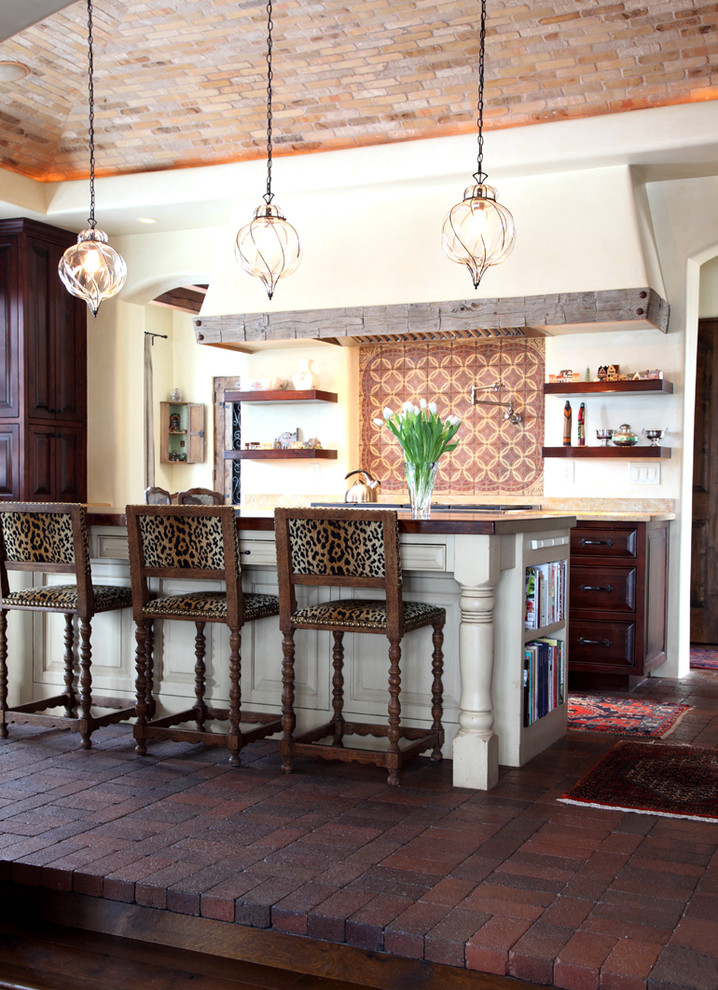 Foto de cocina mediterránea con armarios con paneles con relieve, puertas de armario de madera en tonos medios, suelo de ladrillo y barras de cocina