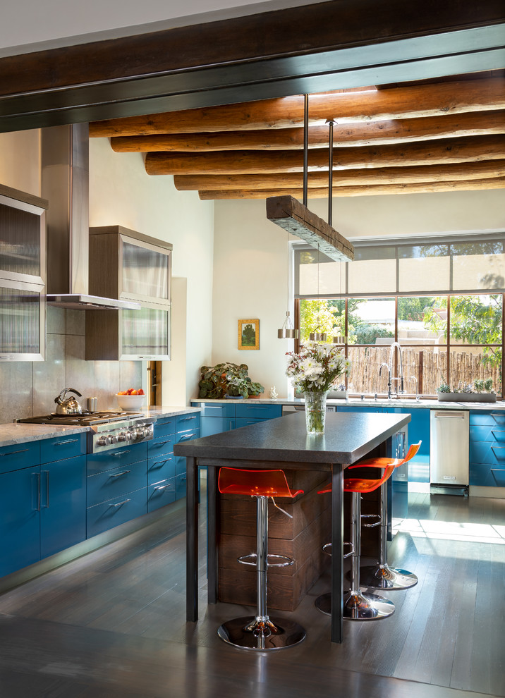 Foto på ett stort eklektiskt vit l-kök, med släta luckor, blå skåp, rostfria vitvaror, mörkt trägolv, en köksö, brunt golv, grått stänkskydd och stänkskydd i cementkakel