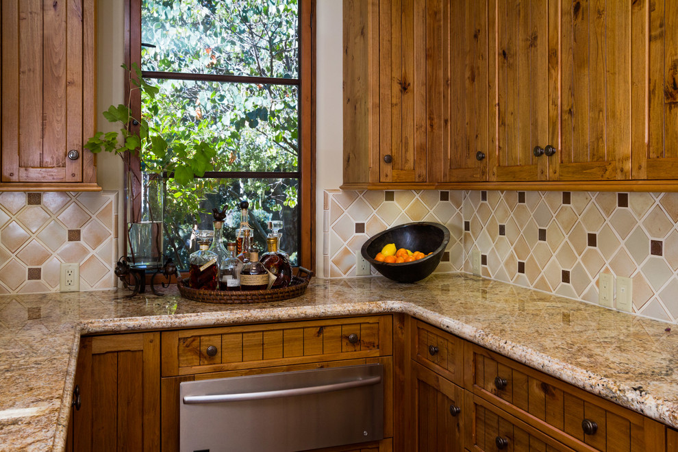 Foto di una cucina abitabile mediterranea con lavello a vasca singola, ante in legno scuro, top in granito, paraspruzzi beige, paraspruzzi con piastrelle di metallo e elettrodomestici da incasso