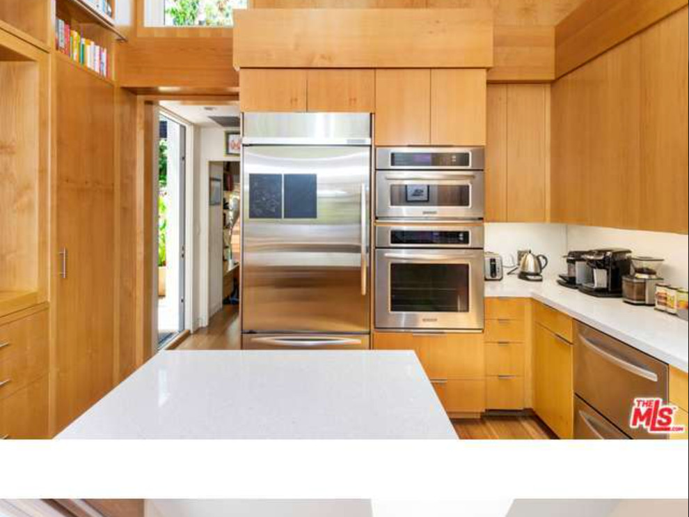 Trendy u-shaped bamboo floor eat-in kitchen photo in Los Angeles with a double-bowl sink, flat-panel cabinets, medium tone wood cabinets, quartz countertops, white backsplash, glass sheet backsplash, stainless steel appliances and an island