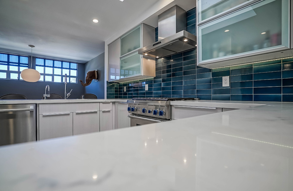 This is an example of a medium sized contemporary u-shaped kitchen pantry in Los Angeles with a submerged sink, flat-panel cabinets, beige cabinets, engineered stone countertops, blue splashback, porcelain splashback, stainless steel appliances, porcelain flooring and no island.