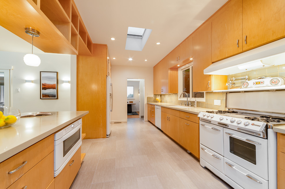 Zweizeilige, Mittelgroße Mid-Century Wohnküche mit Doppelwaschbecken, Mineralwerkstoff-Arbeitsplatte, weißen Elektrogeräten, flächenbündigen Schrankfronten und Halbinsel in Los Angeles