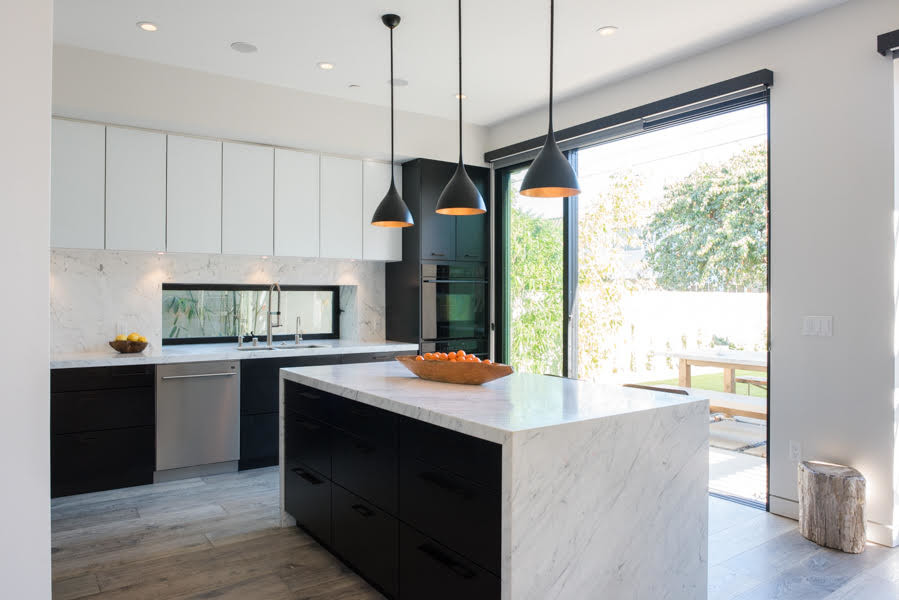 This is an example of a large modern l-shaped open plan kitchen in Los Angeles with a submerged sink, flat-panel cabinets, marble worktops, white splashback, marble splashback, stainless steel appliances, medium hardwood flooring, an island, grey floors, white worktops and black cabinets.