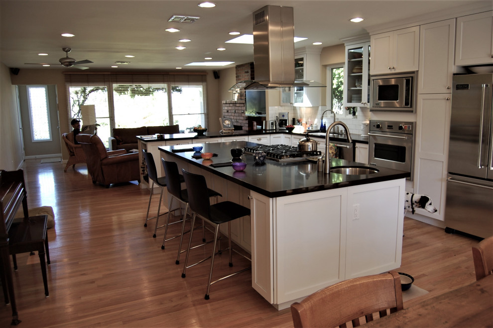 ロサンゼルスにある広いトラディショナルスタイルのおしゃれなキッチン (アンダーカウンターシンク、シェーカースタイル扉のキャビネット、白いキャビネット、クオーツストーンカウンター、白いキッチンパネル、サブウェイタイルのキッチンパネル、シルバーの調理設備、無垢フローリング、茶色い床、茶色いキッチンカウンター) の写真