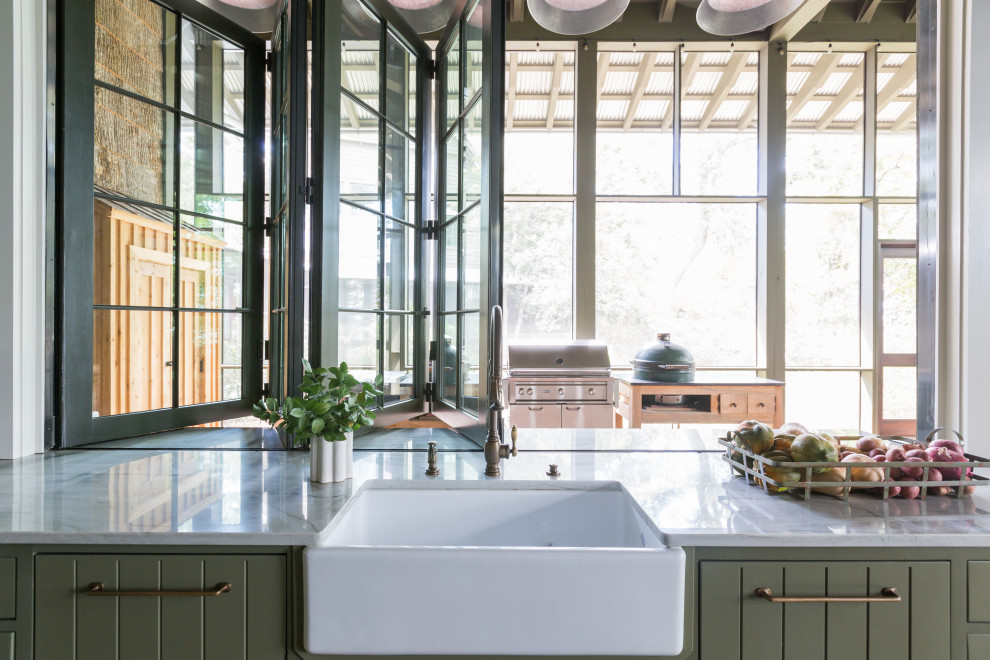 Zweizeilige Urige Küche mit Landhausspüle, grünen Schränken, Elektrogeräten mit Frontblende, braunem Holzboden und Kücheninsel in Sonstige