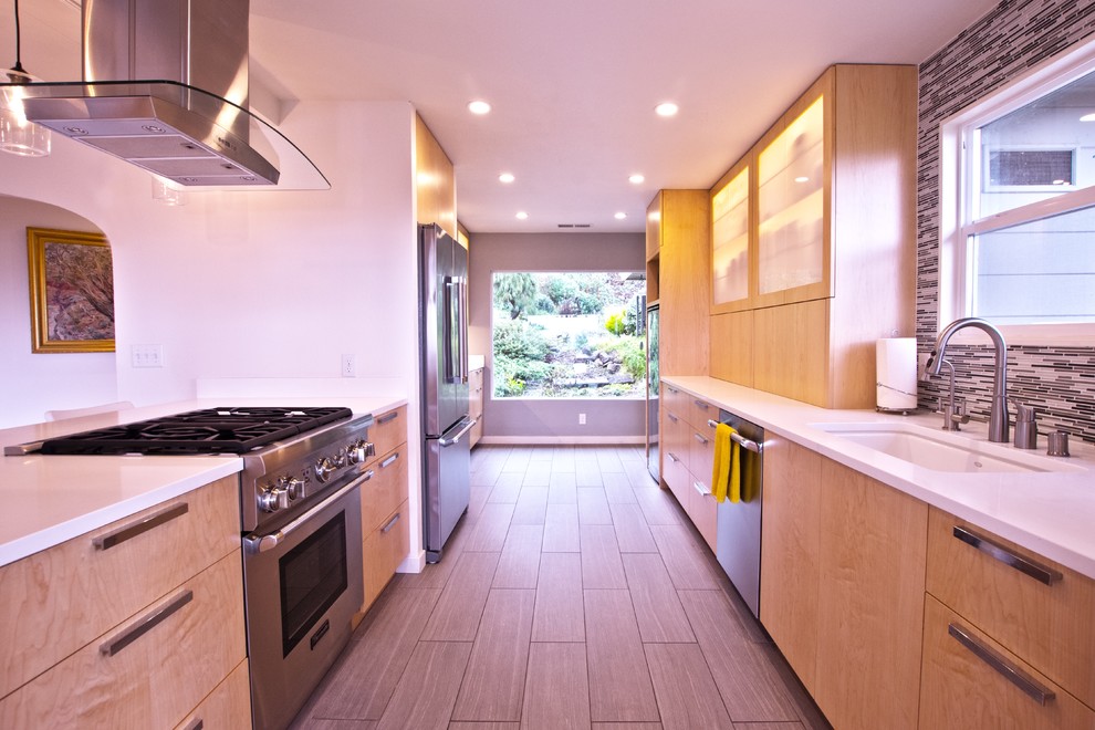 Medium sized modern galley enclosed kitchen in San Francisco with a single-bowl sink, flat-panel cabinets, light wood cabinets, stainless steel appliances and no island.