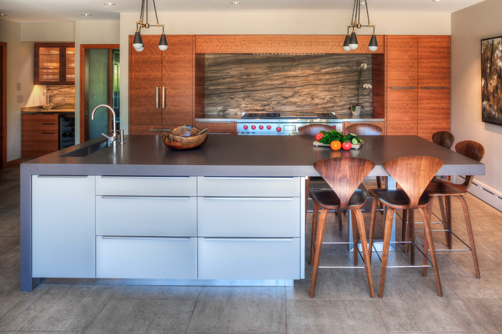 This is an example of a large contemporary galley kitchen in Portland with a submerged sink, flat-panel cabinets, medium wood cabinets, grey splashback, stone slab splashback, stainless steel appliances, porcelain flooring, an island, grey worktops and grey floors.