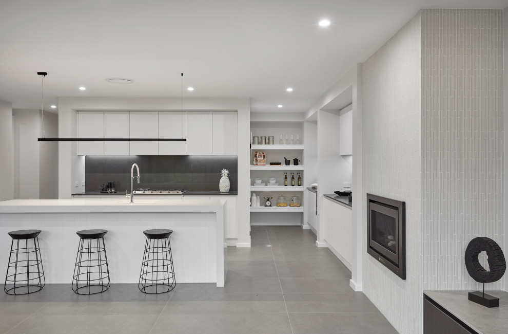 Immagine di una grande cucina minimal con paraspruzzi nero, elettrodomestici in acciaio inossidabile e top bianco