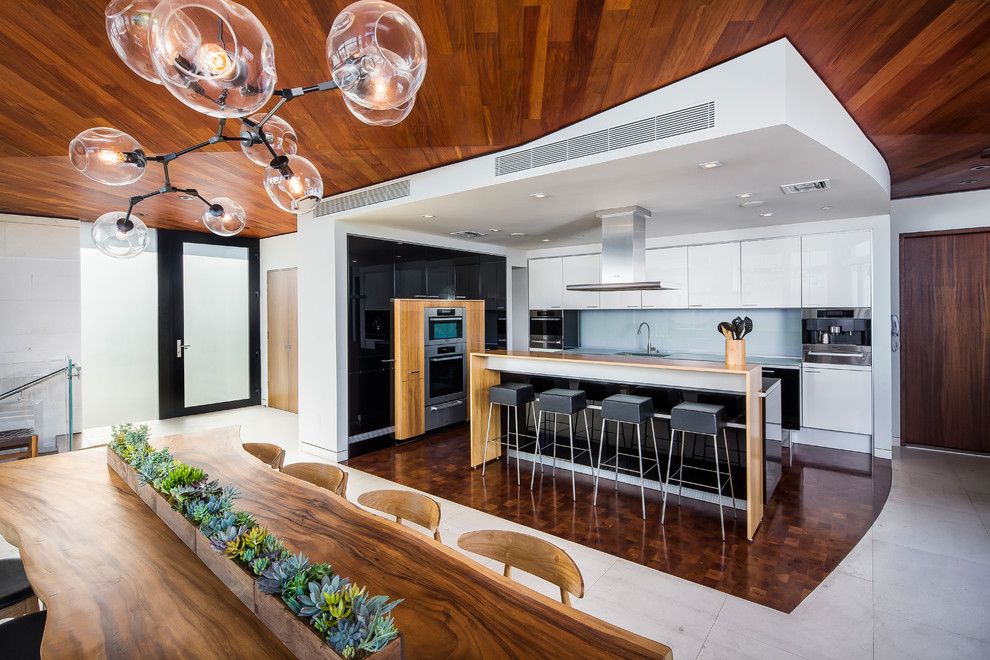 Идея дизайна: большая угловая кухня-гостиная в современном стиле с белыми фасадами, техникой из нержавеющей стали и островом