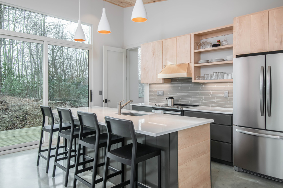 Zweizeilige Moderne Küche mit Unterbauwaschbecken, hellen Holzschränken, Küchenrückwand in Grau, Küchengeräten aus Edelstahl, Betonboden, Kücheninsel, grauem Boden und weißer Arbeitsplatte in Sonstige
