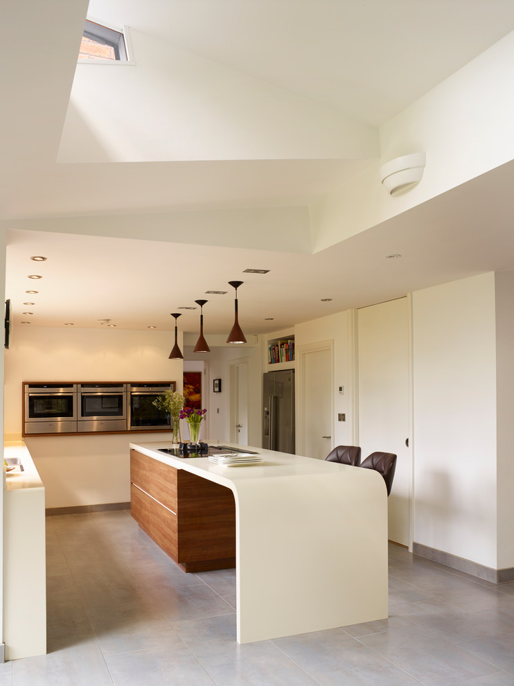 На фото: угловая кухня среднего размера в современном стиле с техникой из нержавеющей стали, плоскими фасадами, белыми фасадами и островом