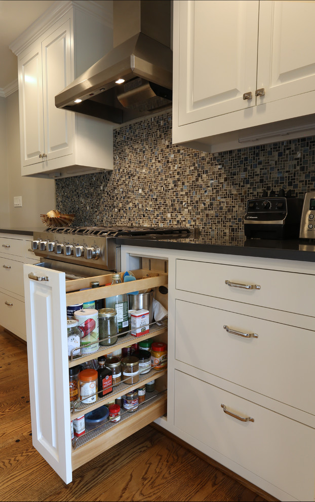 Example of a large transitional medium tone wood floor eat-in kitchen design in Portland with an undermount sink, white cabinets, quartz countertops, multicolored backsplash, glass tile backsplash, stainless steel appliances and an island