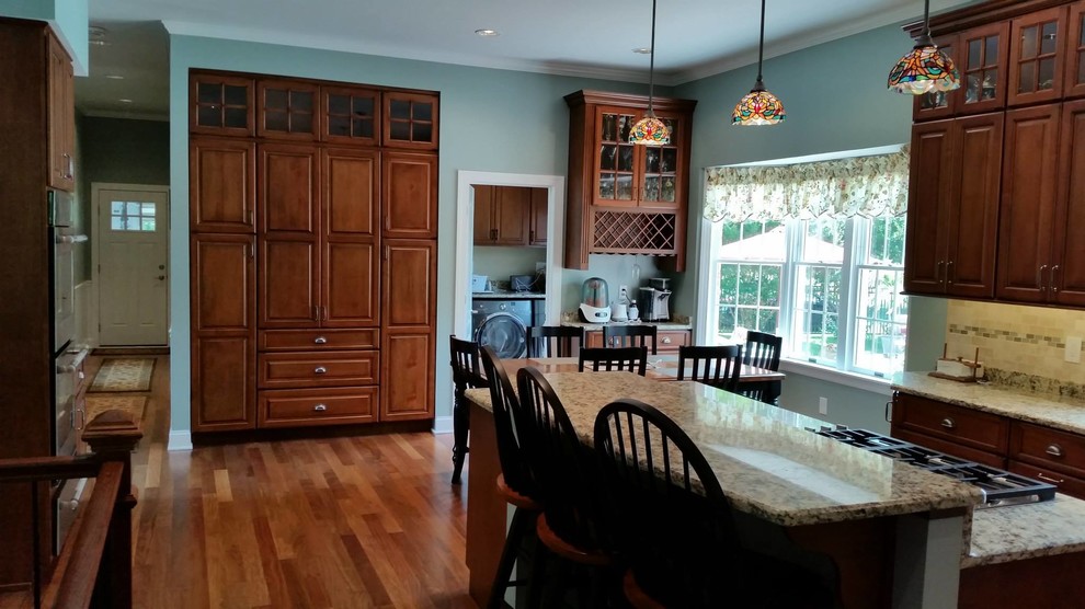 Eat-in kitchen - large traditional l-shaped dark wood floor and brown floor eat-in kitchen idea in Baltimore with an undermount sink, raised-panel cabinets, dark wood cabinets, granite countertops, beige backsplash, ceramic backsplash, stainless steel appliances and an island